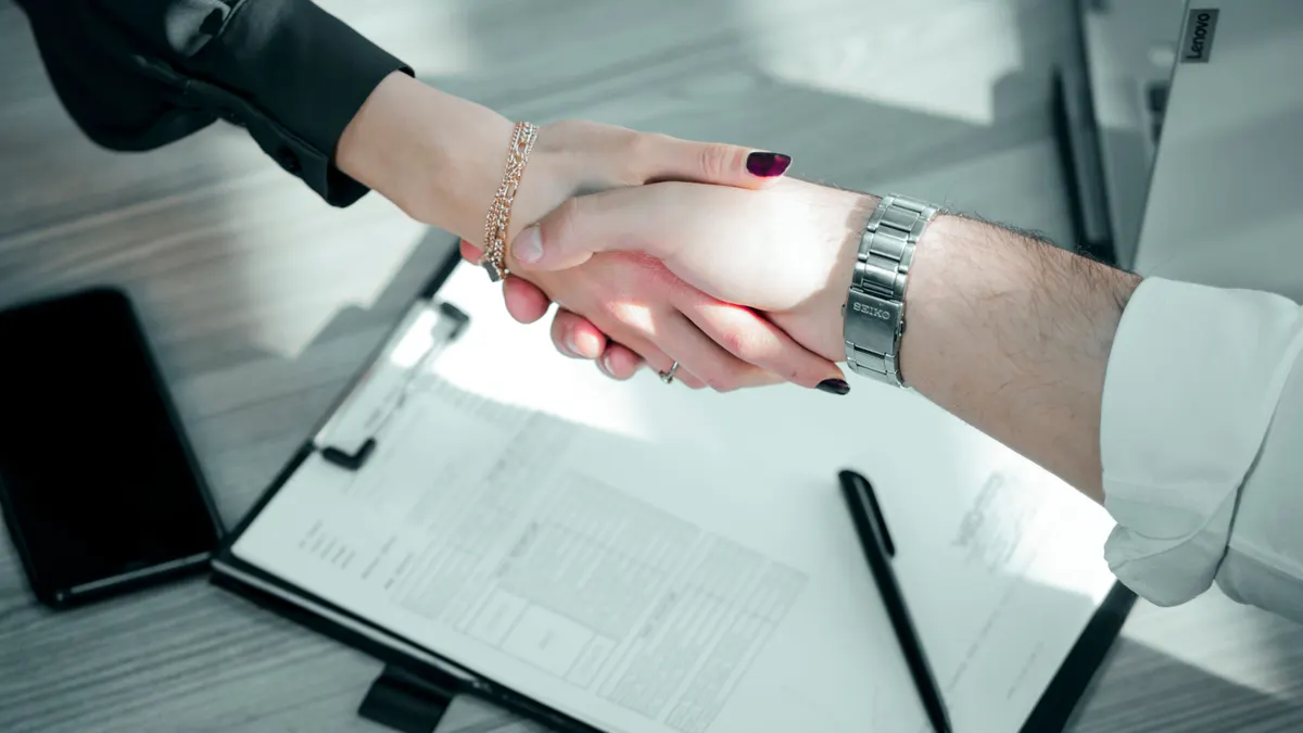 Gros plan sur une poignée de main professionnelle au-dessus d'un contrat, deux mains se serrant.