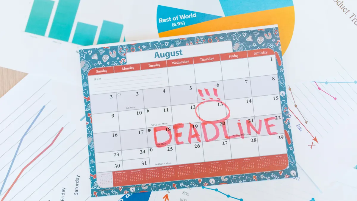 Calendrier d'août coloré sur un bureau, échéance marquée en rouge, entouré de graphiques.