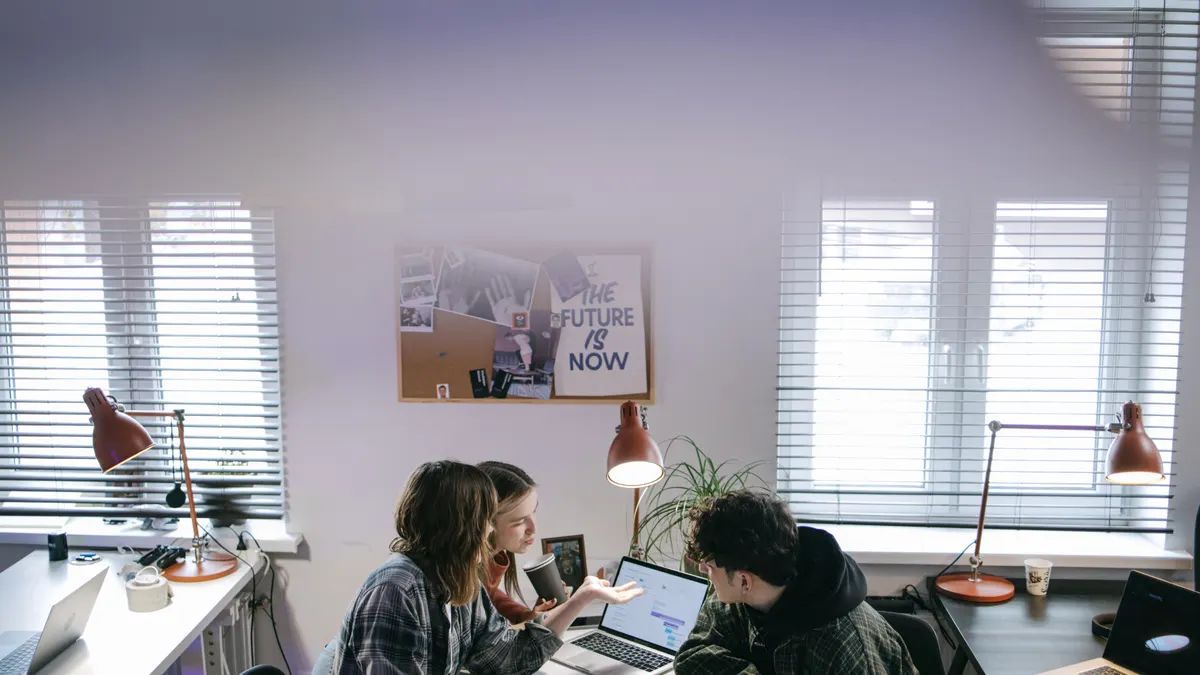 Des collègues utilisent un ordinateur portable et discutent d’idées dans un bureau moderne et lumineux.