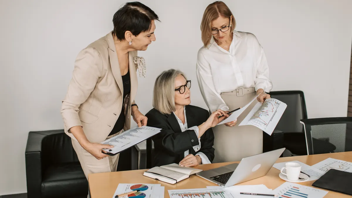 Trois femmes d'affaires seniors discutent de graphiques financiers lors d'une réunion formelle au bureau.