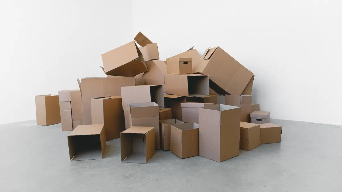 Pile de cartons empilés au sol dans une maison, à la lumière du jour, sur fond blanc